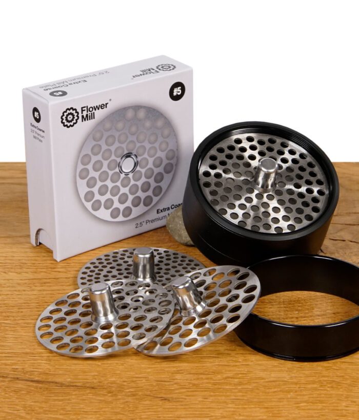 Flower Mill Mahlplatten aus Edeltstahl mit 2,5" Durchmesser mit Flower Mill Grinder auf Holz.