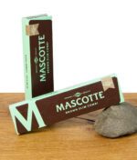 Zwei geschlossene Packungen Mascotte Brown Paper mit Tips King Size Slim mit grün-braunem Design.