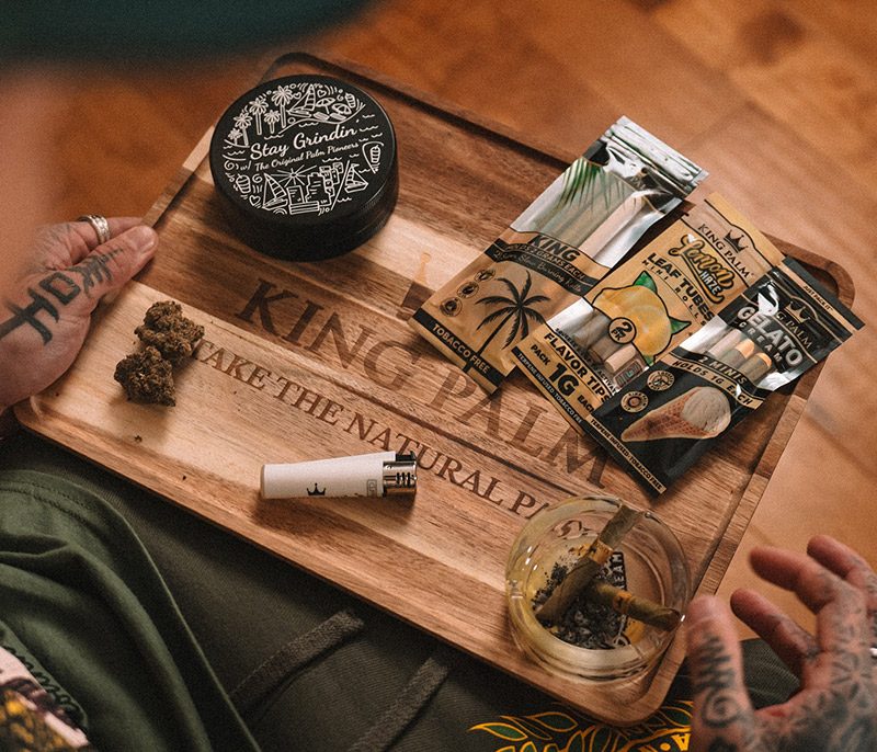 King Palm Zubehör mit Blunts, Grinder, Clipper und Buds auf Holz-Tablett