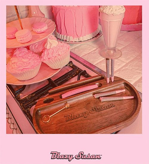 Blazy Susan Rolling Tray mit pinken Papers und Zubehör neben rosa Cupcakes und Macarons im Retro-Stil.