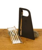 Puffco New Peak Zubehör: Dab Tool mit Halterung und Reinigungsstäbchen auf Holz mit Stein im Hintergrund.