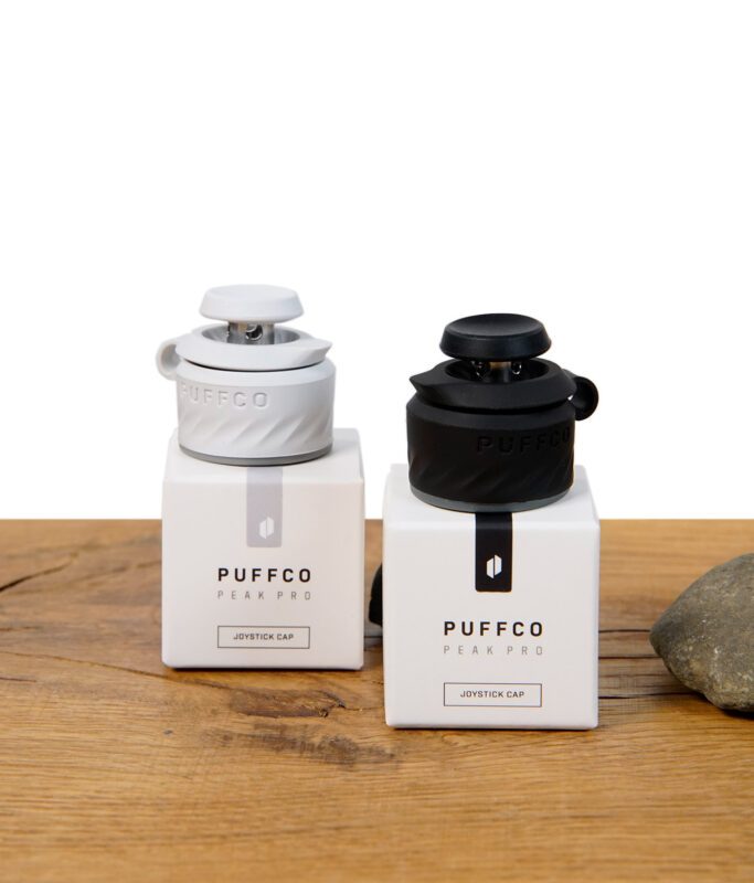 Zwei Puffco Peak Pro Joystick Caps in Schwarz (Onyx) und Weiß (Pearl) auf den jeweiligen Verpackungen