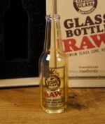 Nahaufnahme der RAW Glasflasche mit Logo und Schriftzug auf der Vorderseite