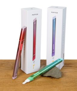 Alle drei Edition der Gemstone Edition vom Puffco Hot Knife mit Verpackungen auf Holz.