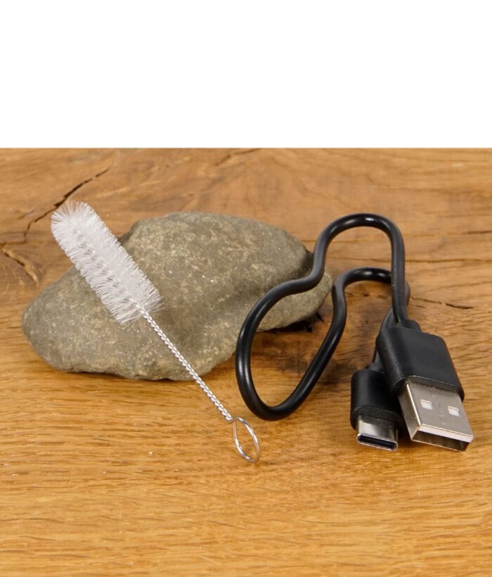 Reinigungsbürste und USB-C Ladekabel für den Black Leaf Cigar X1 Vaporizer, abgelegt auf einem Stein.