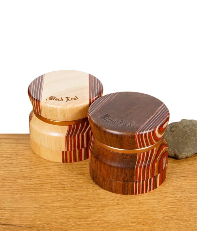 Zwei Black Leaf Grinder aus Holz mit Aluminiumkern auf einem Holztisch