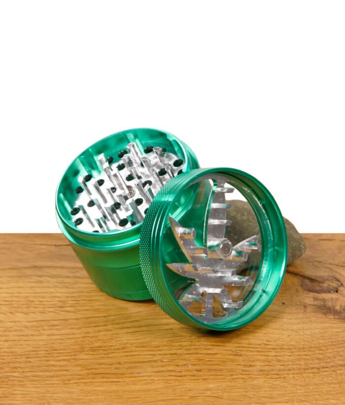 Grüner Grinder geöffnet, Deckel mit Hanfblattmuster liegt seitlich vor dem Mahlwerk