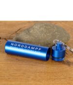 Geöffneter Norddampf Capsule Caddy in Blau mit Schraubdeckel und Schlüsselring auf Holztisch