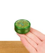 Grüner Leafly-Grinder liegt auf der geöffneten Handfläche zur Größenveranschaulichung