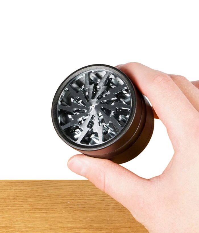 Hand hält Thorinder Grinder mit sichtbaren Schneidezähnen unter Acrylfenster