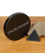 Schwarzer runder Grinderdeckel mit „THORINDER“-Schriftzug neben dreieckigem Schaber