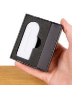 Der weiße Cloak Vaporizer liegt passgenau in einer schwarzen Schaumstoffverpackung und wird von einer Hand gehalten.