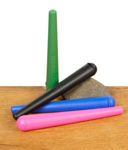 Vier THE BULLDOG Jointtubes in Grün, Schwarz, Blau und Pink auf einem Stein liegend, auf Holzoberfläche.