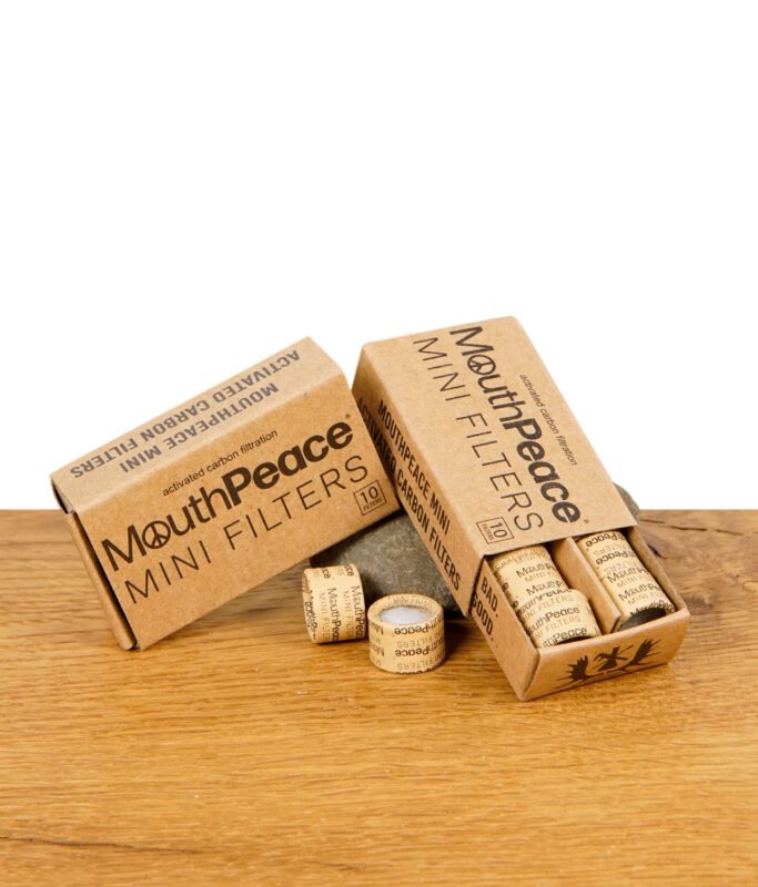 Zwei Packungen MouthPeace Mini Filter aus Karton, eine geöffnet mit sichtbaren Aktivkohlefiltern auf Holzuntergrund.