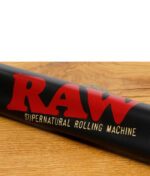 Nahaufnahme der RAW Supernatural Rolling Machine mit großem roten RAW-Logo auf schwarzer Metalloberfläche.