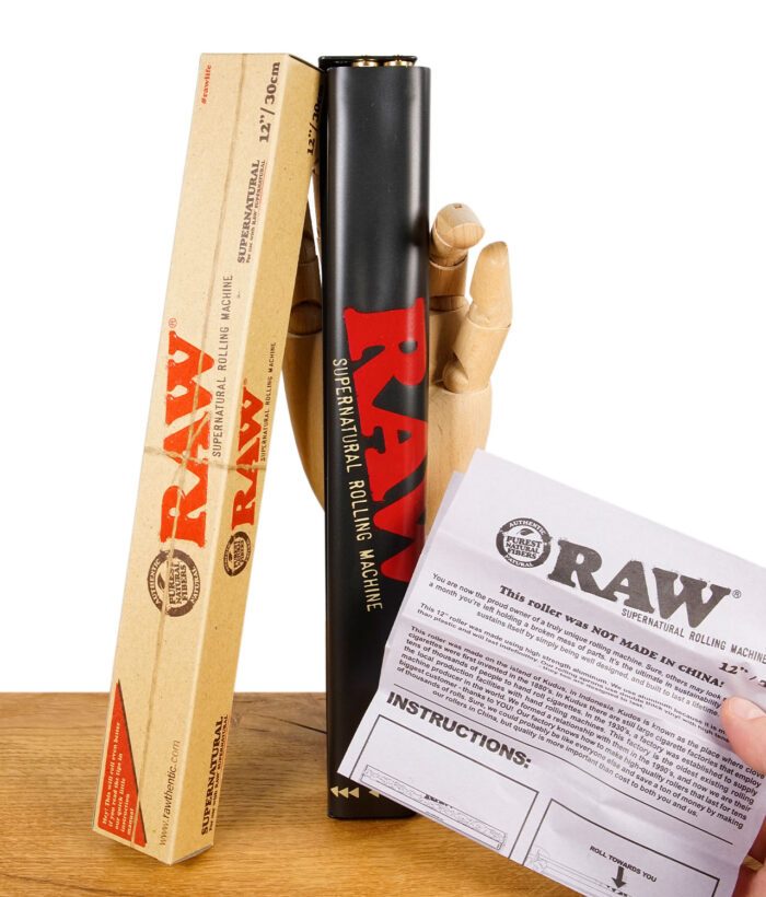 RAW Huge Roller neben geöffneter Verpackung und gedruckter Anleitung, gehalten von einer Holzhand.