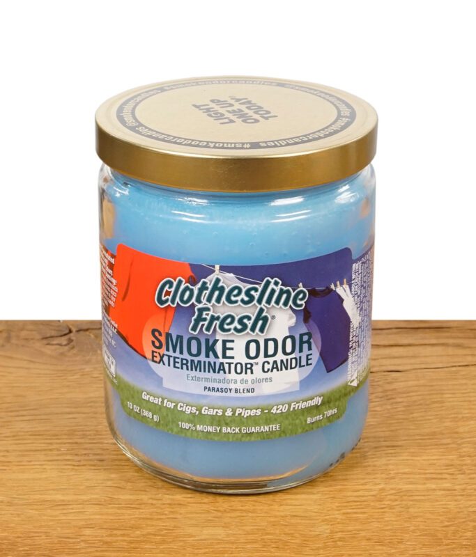 Geschlossene Smoke Odor Exterminator Candle in der Variante Clothesline Fresh mit goldenem Metalldeckel und farbigem Etikett.