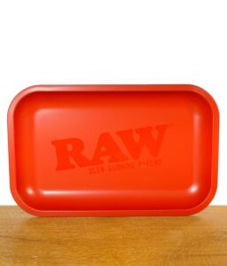 Rotes RAW Rolling Tray mit matter Oberfläche und RAW-Logo in der Mitte, auf Holztisch stehend.