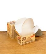 Geöffnete Verpackung der RAW Classic Gum Strips mit einem herausgezogenen Streifen veganem Klebegummi
