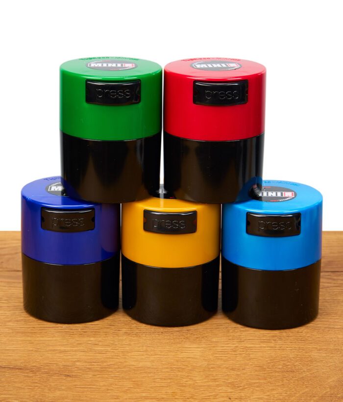 Fünf farbige Tightvac MINIVAC Dosen (grün, rot, blau, gelb, hellblau) nebeneinander auf Holz platziert.