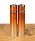 Zwei Clipper Feuerzeuge mit kupferfarbenem Farbverlauf nebeneinander.