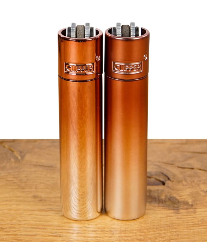 Zwei Clipper Feuerzeuge mit kupferfarbenem Farbverlauf nebeneinander.