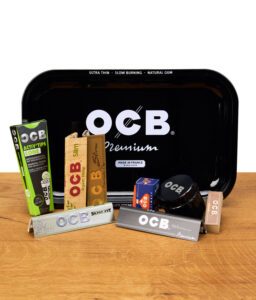 Komplettes OCB Starterset mit Papers, Filtern, Grinder und Metalltray auf Holzfläche.