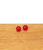 Zwei rote Rubin Pearls aus Glas nebeneinander auf einer Holzfläche