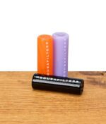 Drei Medusafilters Glasfilter in Orange, Lila und Schwarz auf Holzfläche, schwarzer Filter liegt vorne