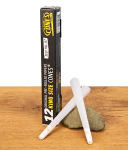 Zwei Original Cones King Size auf einem Stein arrangiert, im Hintergrund die aufrecht stehende Verpackung.