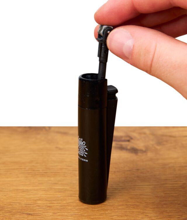 Clipper Feuerzeug mit herausgezogener Zündmechanik, gehalten an der Oberseite.