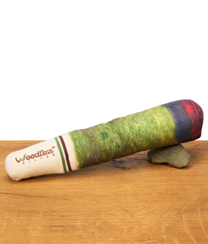 Weedlez Hundespielzeug in Joint-Optik liegend auf Holzoberfläche mit Stein zur Stabilisierung