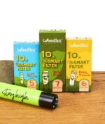 Drei Packungen Weedlez Smart Filter mit den Varianten Slim Trino 5 mm, Big Flow 7 mm und Phil Trino 6 mm vor einem grünen Feuerzeug mit der Aufschrift ‚stay high‘.