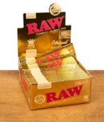 Offene Verkaufsbox mit RAW Ethereal King Size Slim Papers in glänzendem Golddesign, alle Heftchen ordentlich gestapelt.