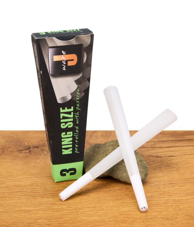 Zwei Jware King Size Cones liegen vor der schwarz-grünen 3er-Packung auf einem Holztisch.