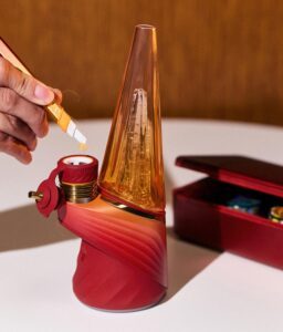 Ein mit dem Hot Knife befüllter Puffco Peak Pro Daybreak auf weißem Tisch vor einer Holzwand