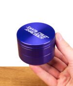 Lila Santa Cruz Shredder Grinder in einer Hand gehalten