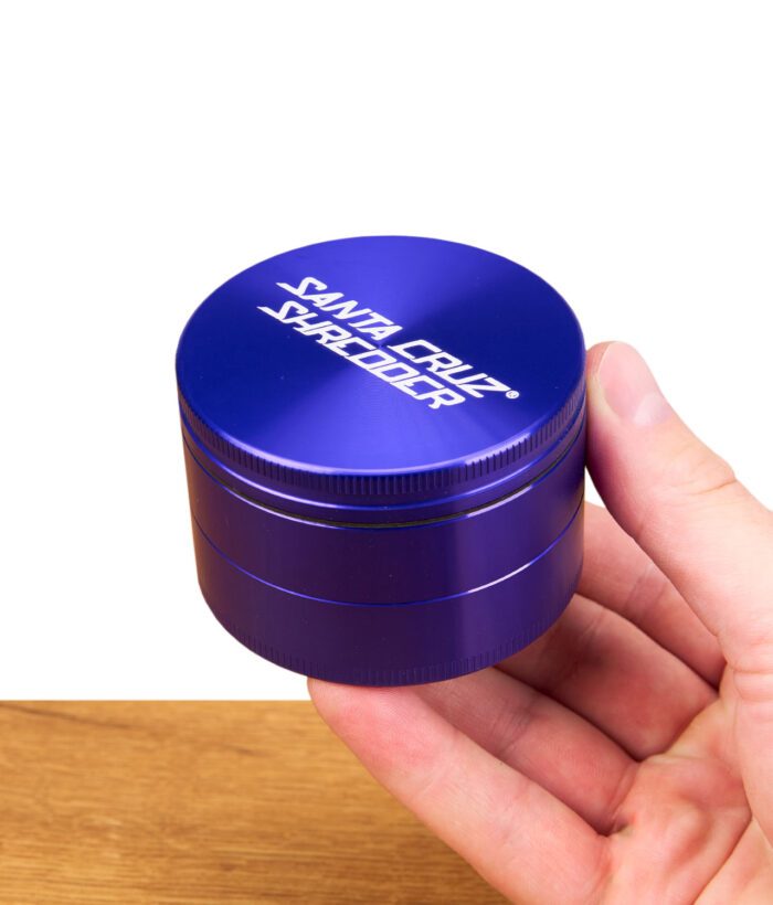 Lila Santa Cruz Shredder Grinder in einer Hand gehalten