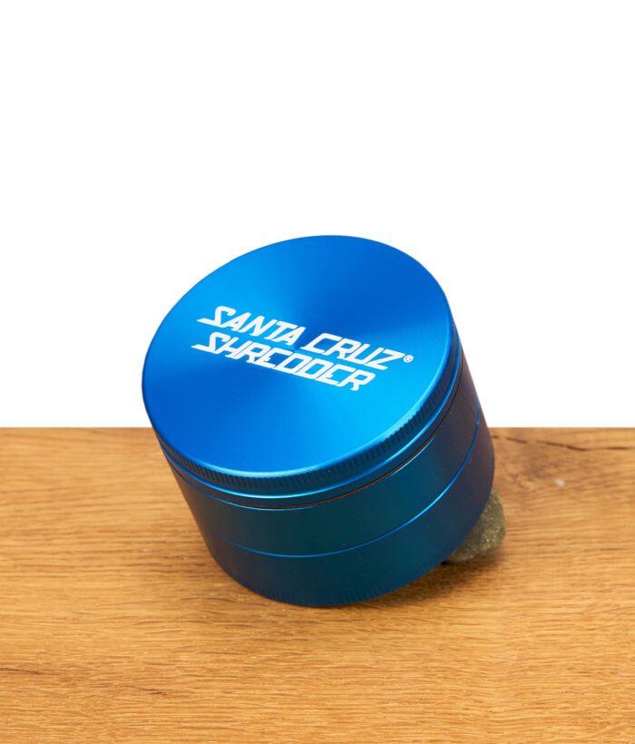 Blauer Santa Cruz Shredder Grinder auf Holzfläche