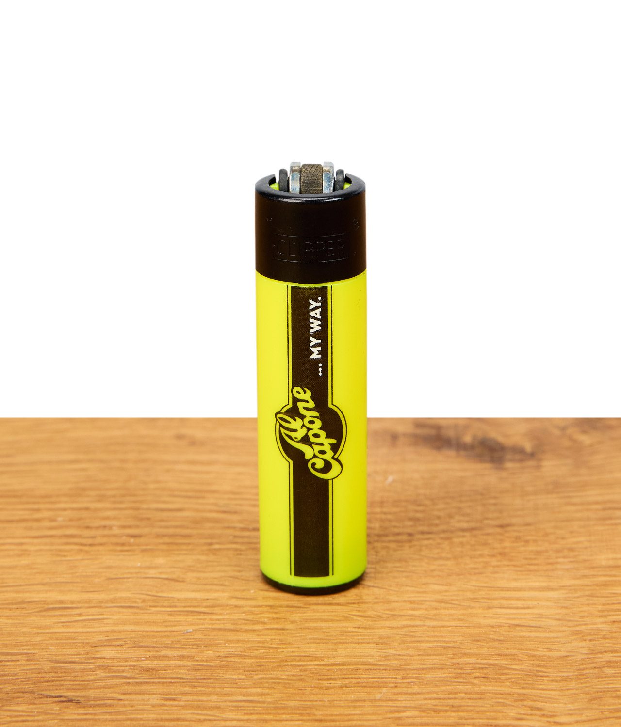 Clipper-Al-Capone-png Clipper Feuerzeug mit Al Capone Logo in Neon-Gelb auf Holzuntergrund