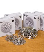 Alle Flower Mill 2,0" Mahlplatten in Nahaufnahme präsentiert, vor den Verpackungen der Plates.