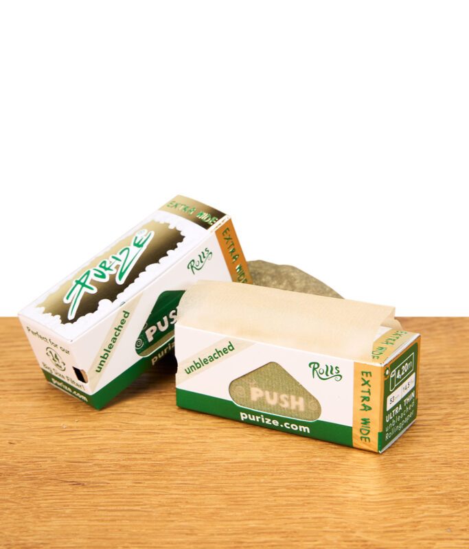 Ungebleichte, extra breite Roll-Papiere in grüner Verpackung mit PUSH-Mechanismus auf Holztisch.