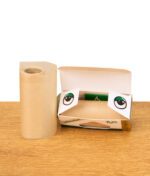 Geöffnete Verpackung mit brauner Roll-Papierrolle und auffälligen Augen-Motiven auf dem Karton, Produkt auf Holzfläche.