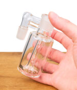 Blaze Glass Recycle Vorkühler: Hand hält den gläsernen Vorkühler mit Duschkopfdiffusor über einem Holztisch, Blaze Logo erkennbar.