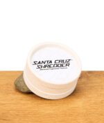 Weißer Hanf Grinder von Santa Cruz angelehnt an einem Stein auf einem Holzbrett