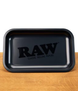 Schwarzes RAW Classic Rolling Tray mit großen, schwarzen Logo in der Mitte steht einzeln auf einem Holztisch.
