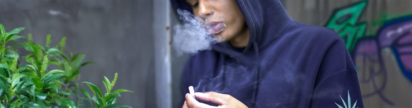 Person raucht Joint diskret mit Kapuze. Will das high sein verstecken.