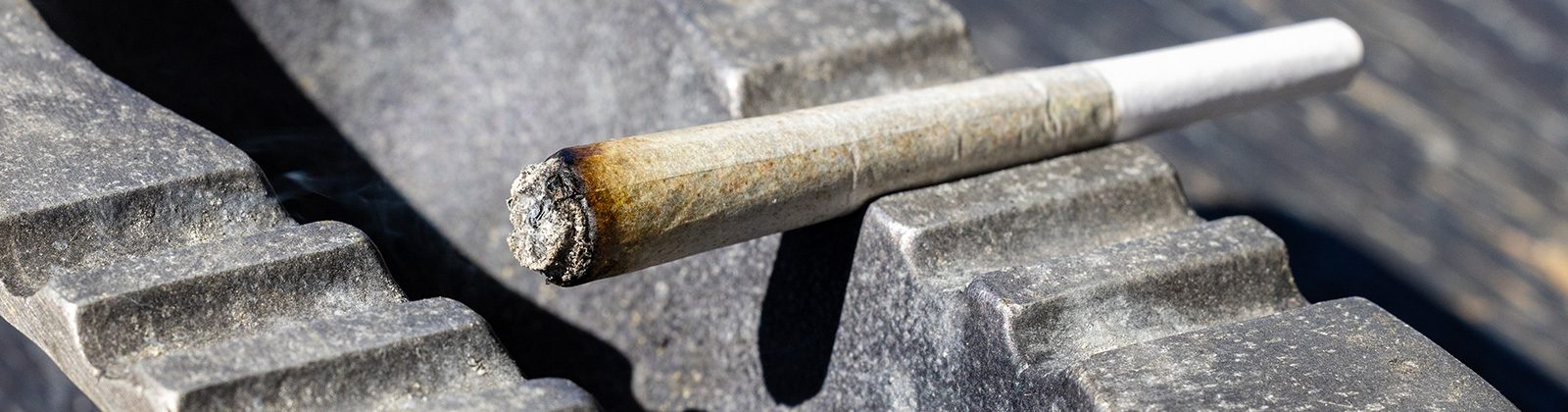 Ein Joint mit weißer Asche liegt im Aschenbecher.