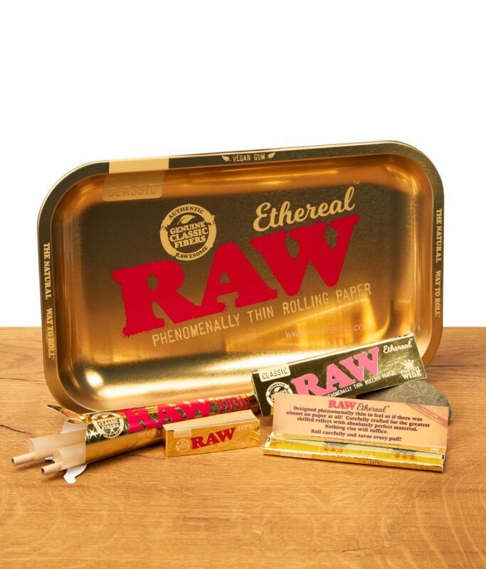 RAW Ethereal Bundle komplett: goldenes Rolling Tray, Classic Papers, Cones und Tips, auf Holzoberfläche arrangiert, Produktset für Rolling Papers.