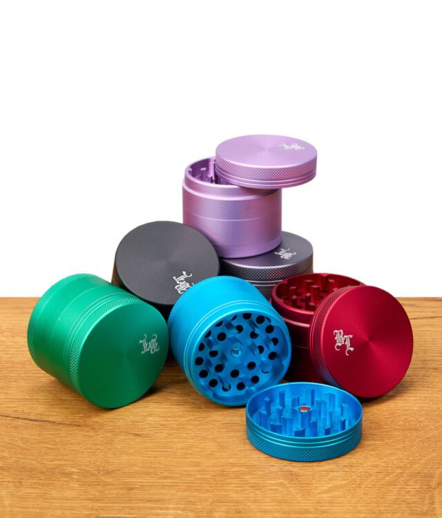 Mehrere Black Leaf Aluminium Grinder Matt 50mm in verschiedenen Farben, teilweise geöffnet, auf Holztisch verteilt